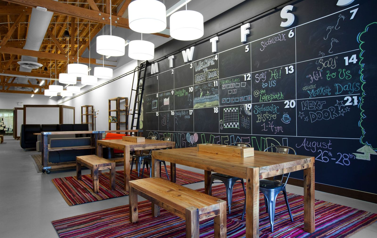 Chalk calendar wall beside reclaimed wood tables on striped rugs