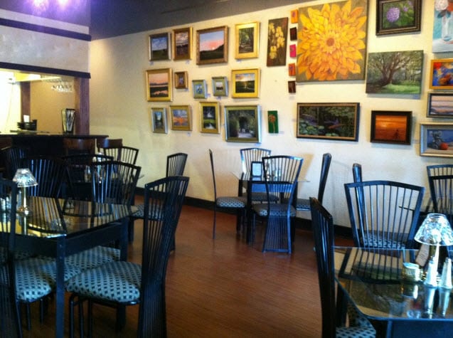 Dining room with black spindle chairs and a wall of framed paintings