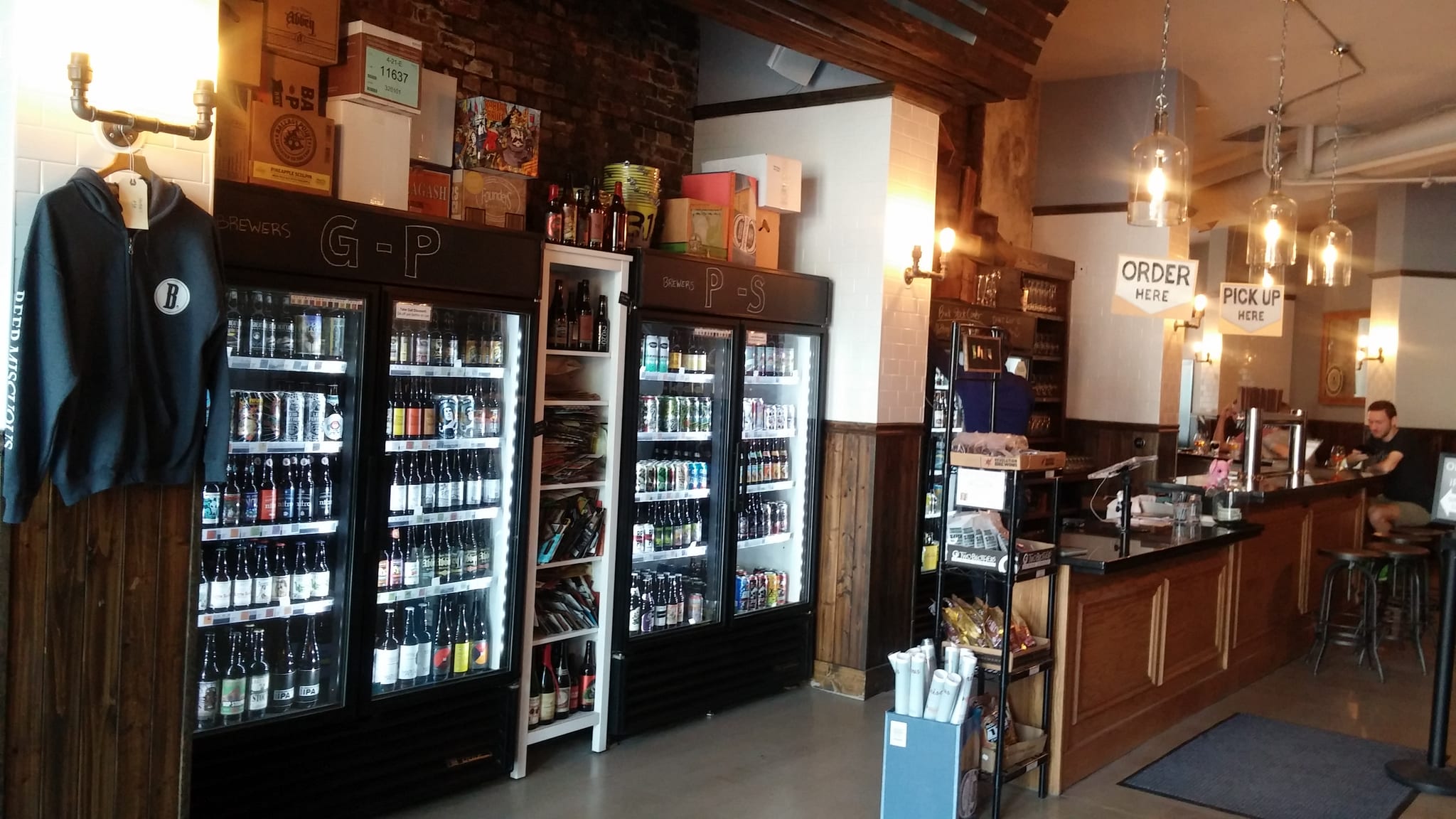 Glass-door beer coolers and shelves facing a bar with Order Here signs