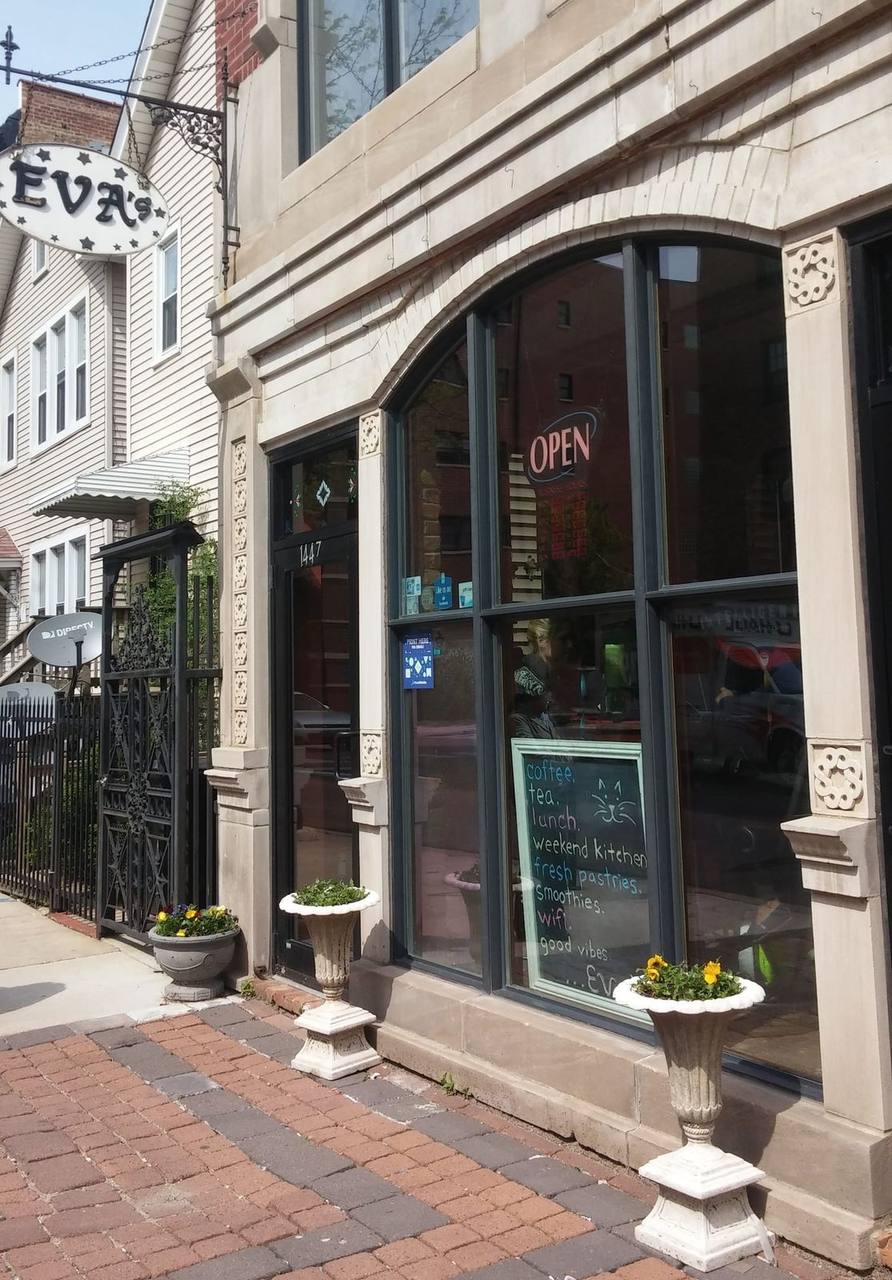 Corner storefront with hanging Evas sign, arched window and flower urns
