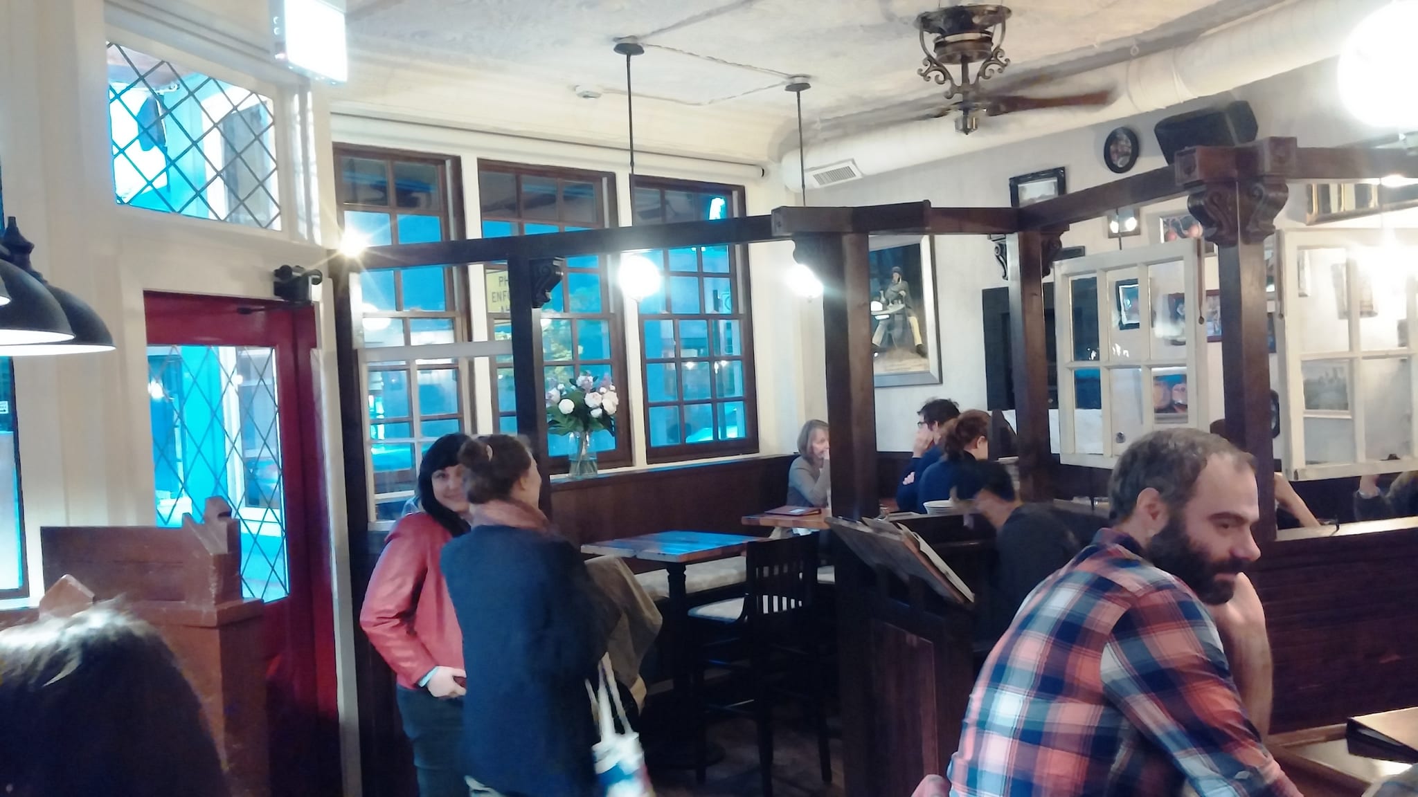 Busy pub dining room with dark wood beams, booths and leaded windows