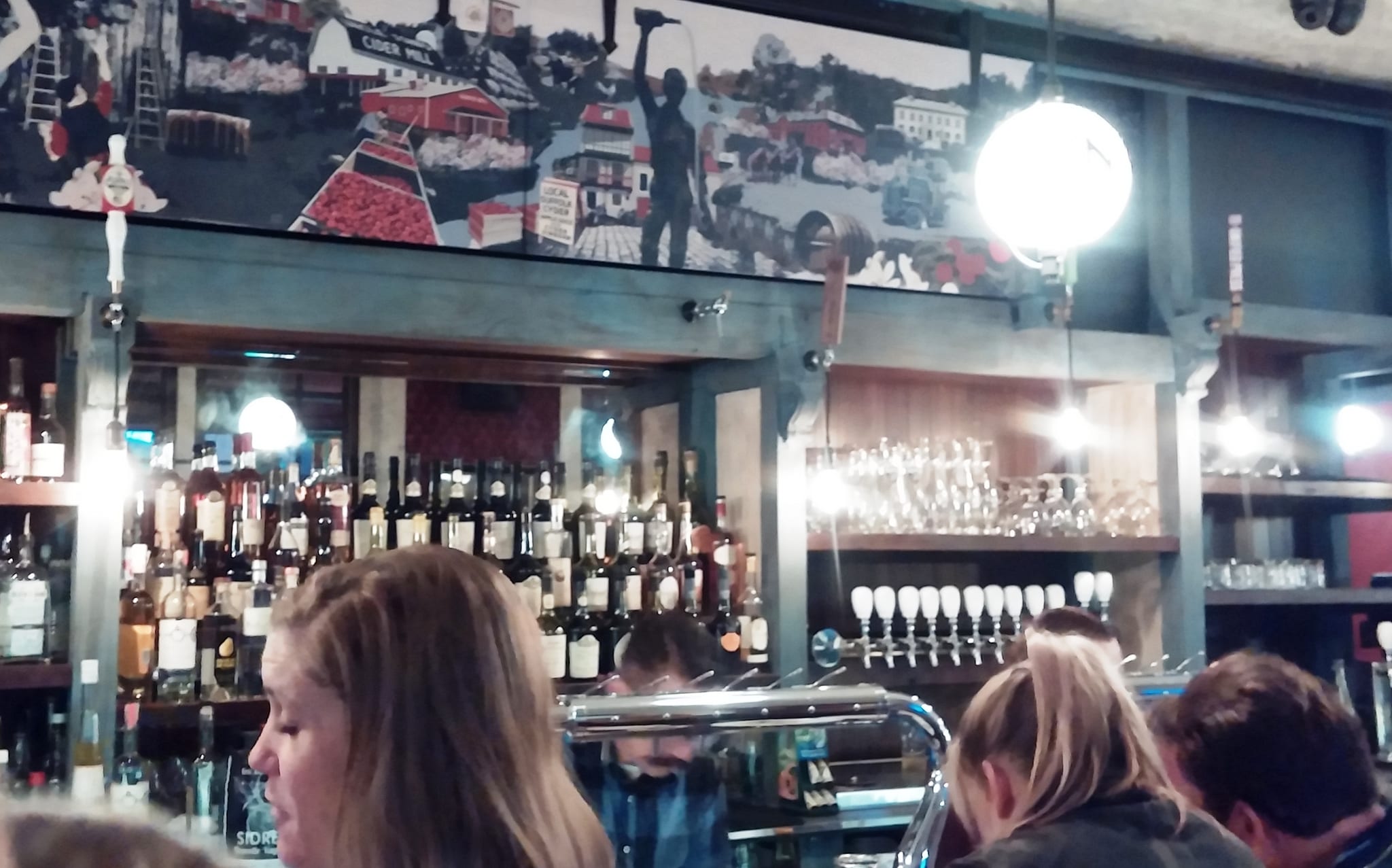 Back bar with cider taps, bottle shelves and a cider-mill mural above