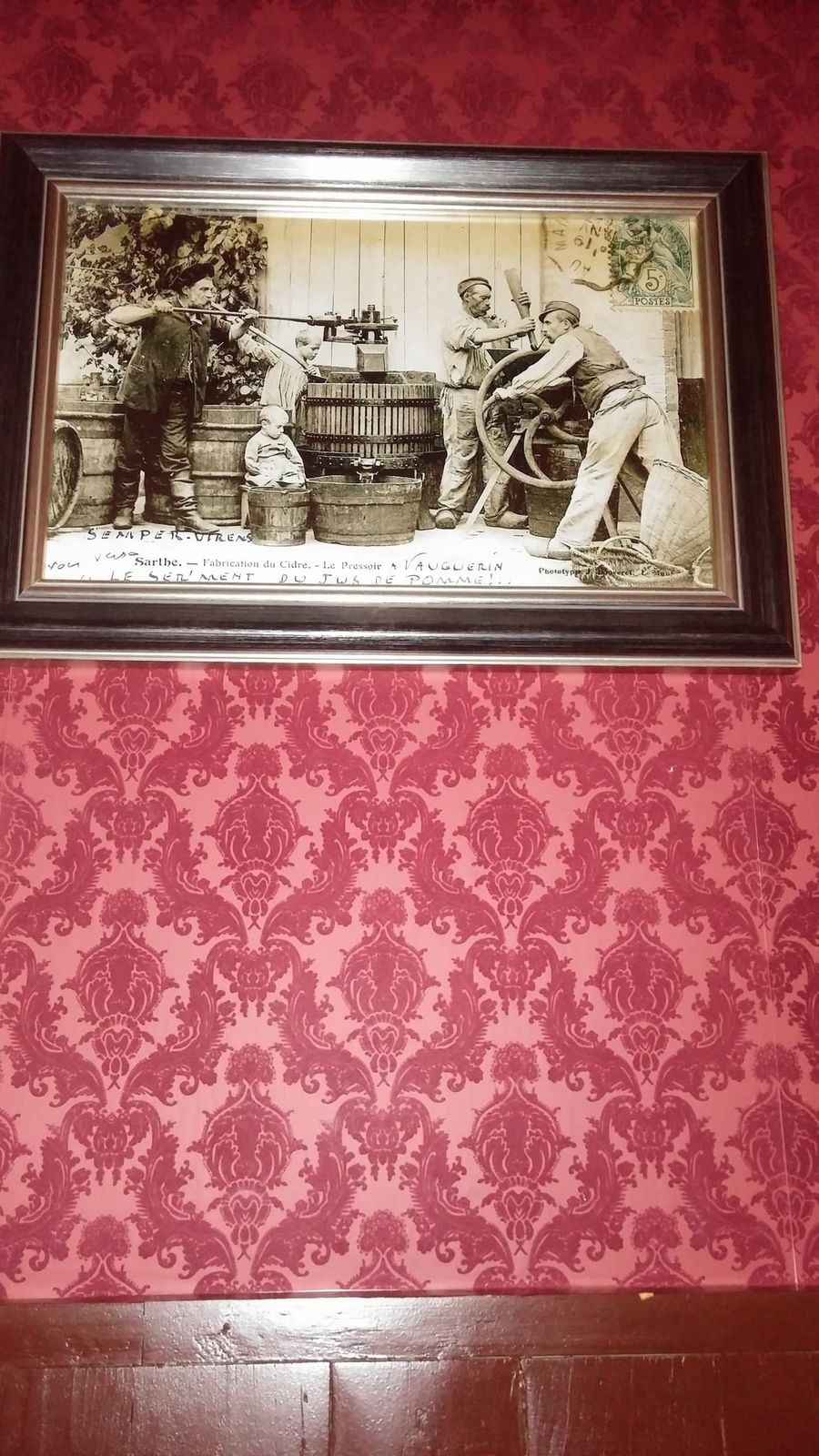 Framed vintage postcard of cider pressing on crimson damask wallpaper