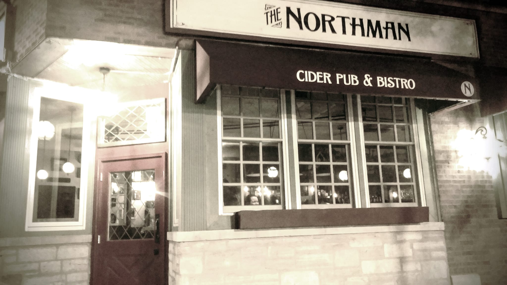Corner storefront at night with awning reading Cider Pub and Bistro