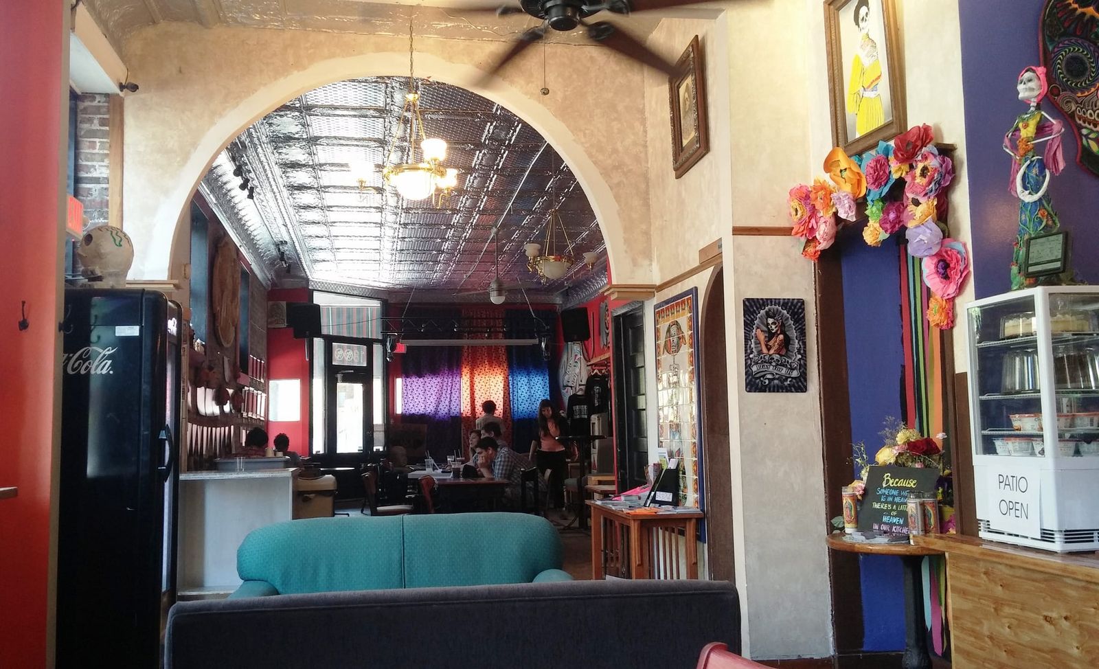 Cafe interior with tin-ceiling archway, sofas and Day of the Dead art