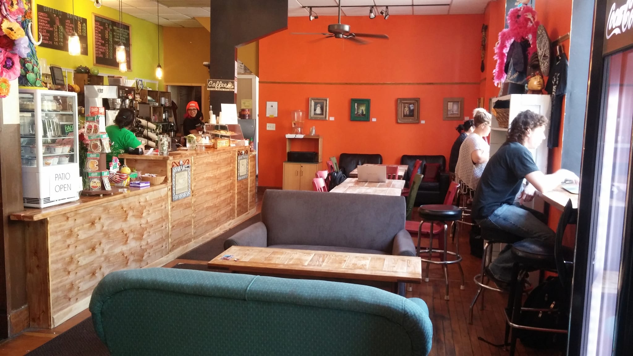 Wooden counter and chalkboard menus, sofas facing a bright orange wall