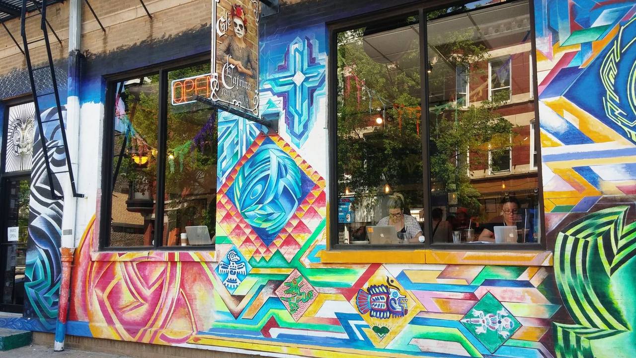 Storefront covered in a bright geometric mural, customers at window laptops