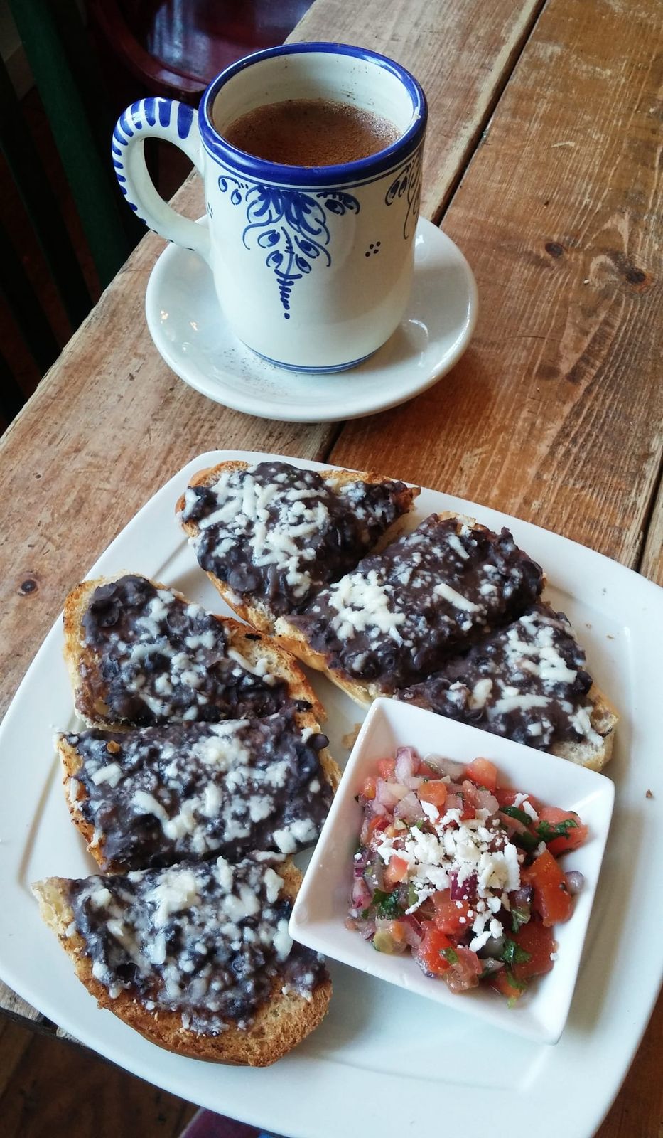 Bean and cheese toasts with pico de gallo beside a painted mug