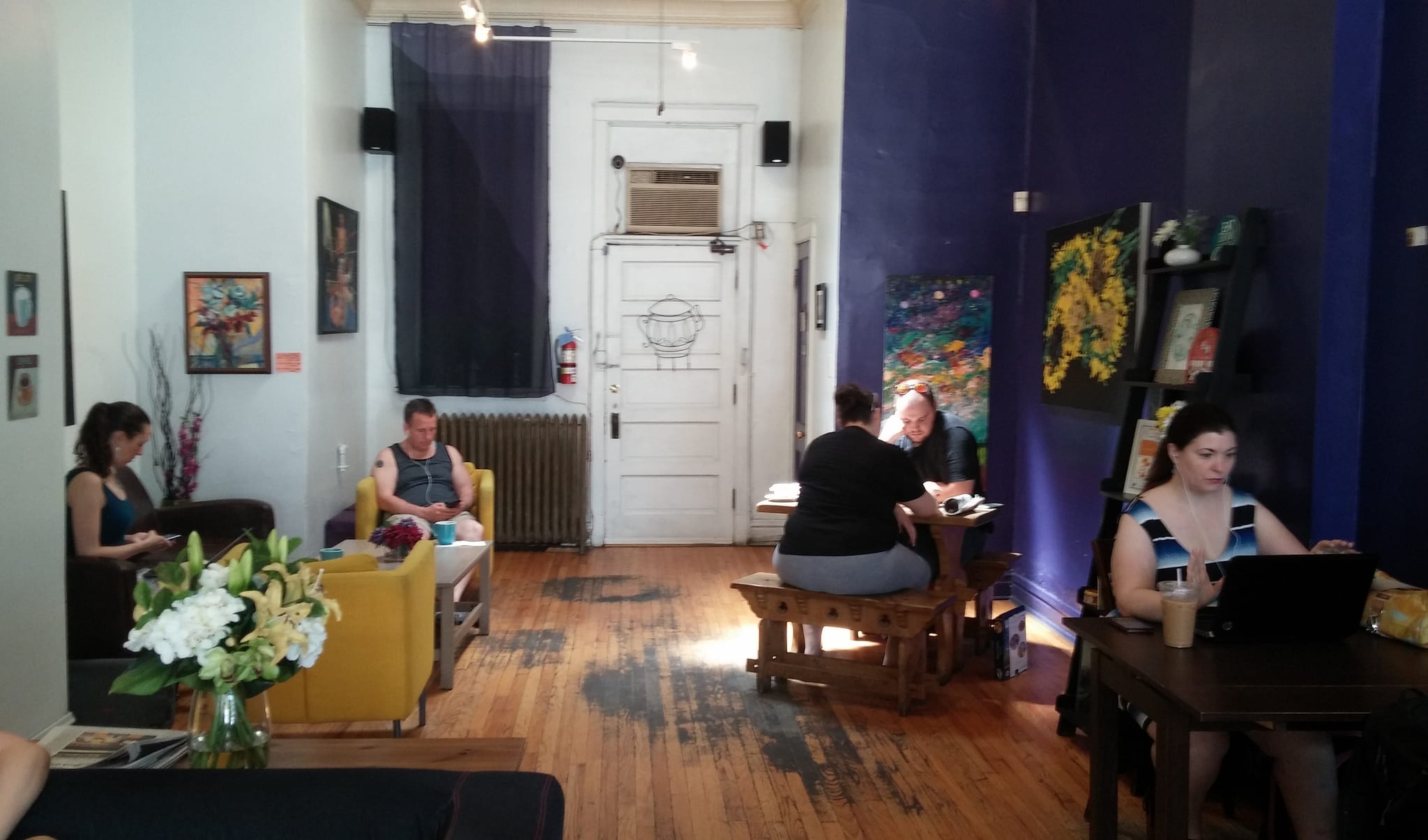 Lounge area with yellow armchairs, wood floors and artwork on purple walls