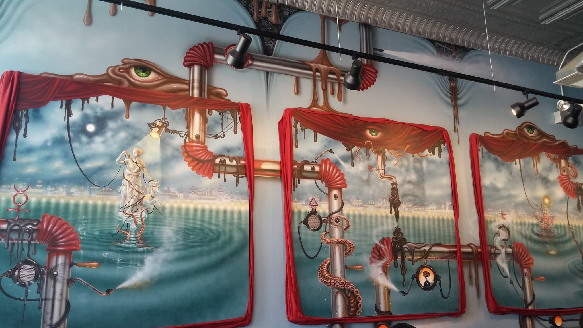 Surreal mural of dripping pipes and seascapes under track lighting