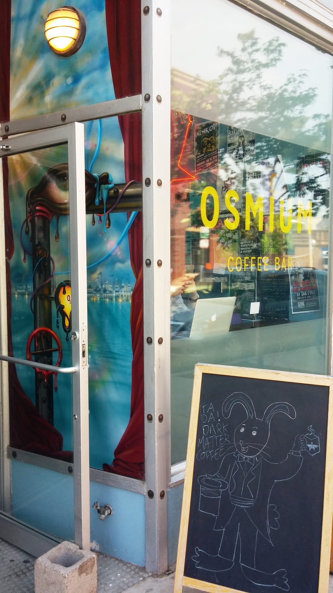 Storefront door with painted mural and Osmium Coffee Bar window lettering