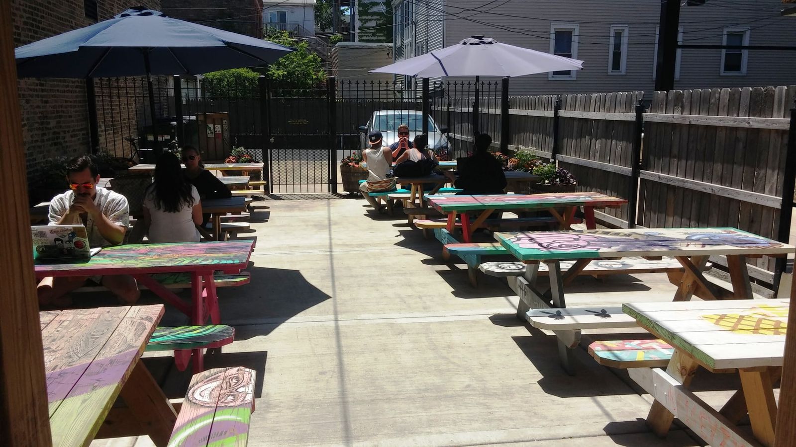 Patio of brightly hand-painted picnic tables under sun umbrellas