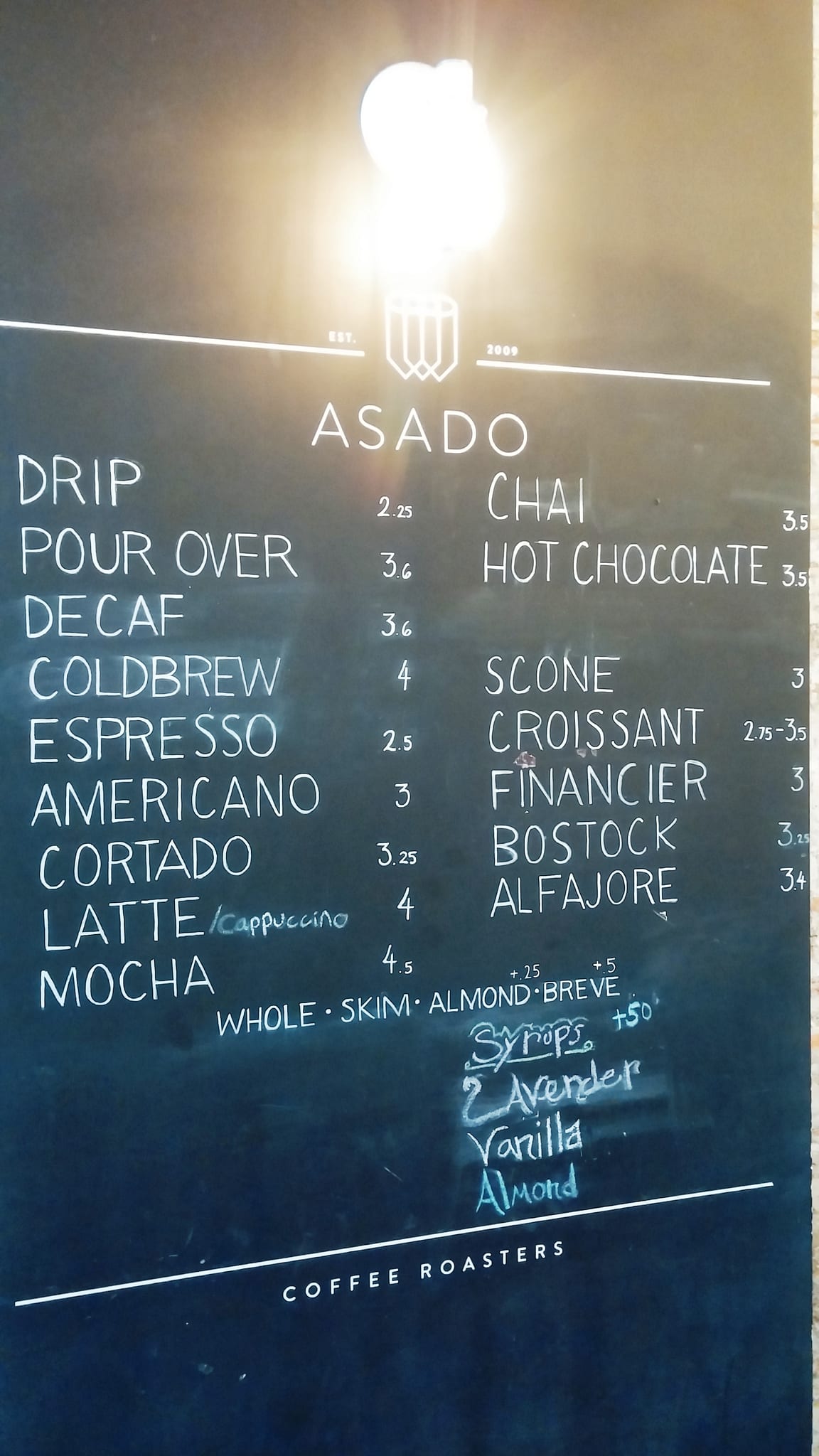 Chalkboard menu listing espresso drinks, pastries and syrup options