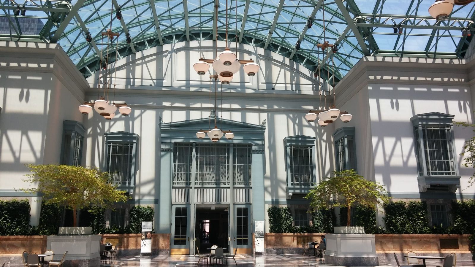 Vaulted glass skylight above a pale classical facade and cafe seating