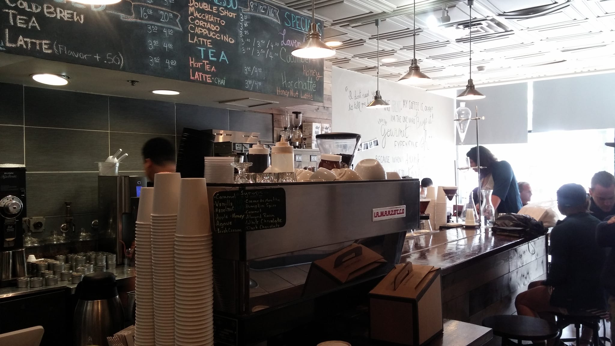 Espresso machine and stacked cups under a chalkboard drink menu