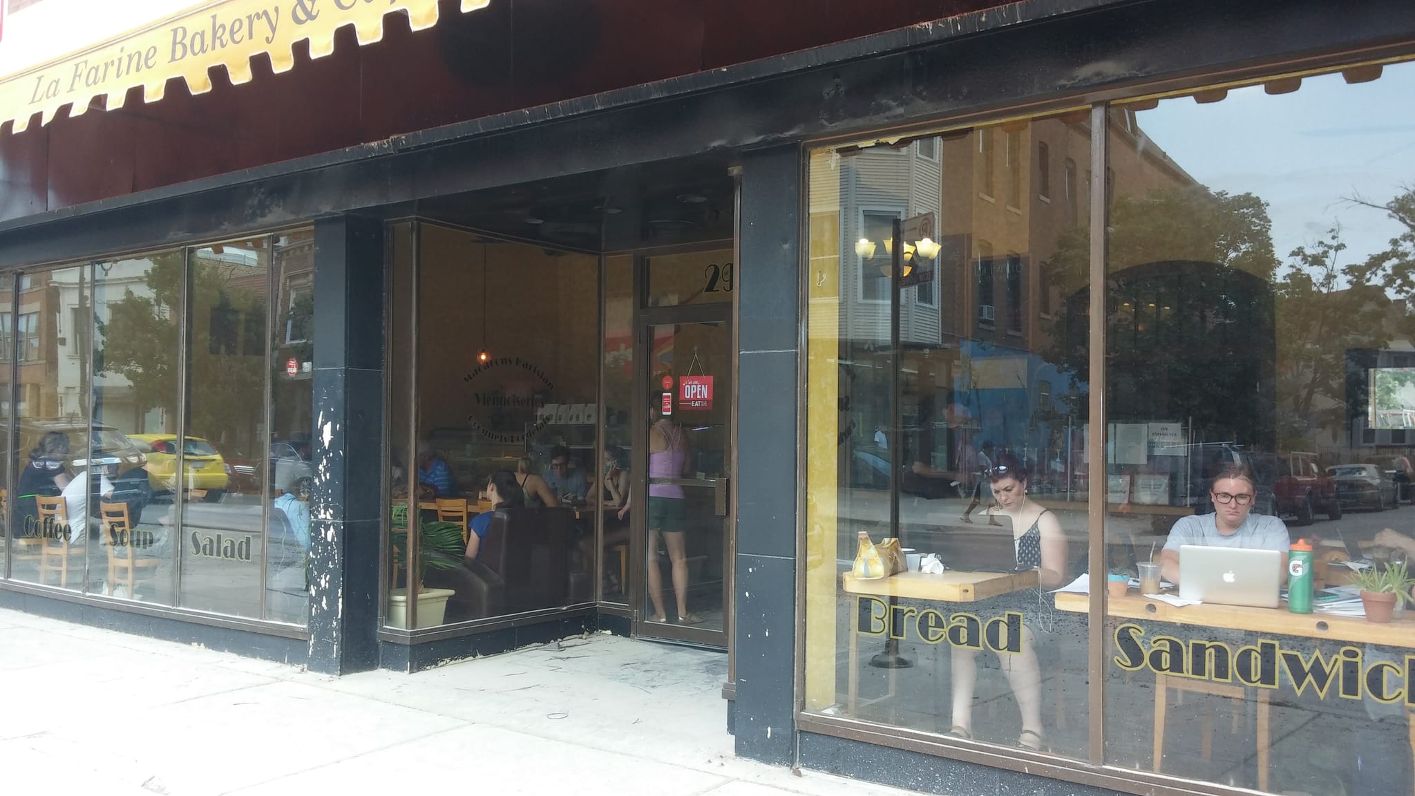 Corner bakery storefront with large windows and customers working inside