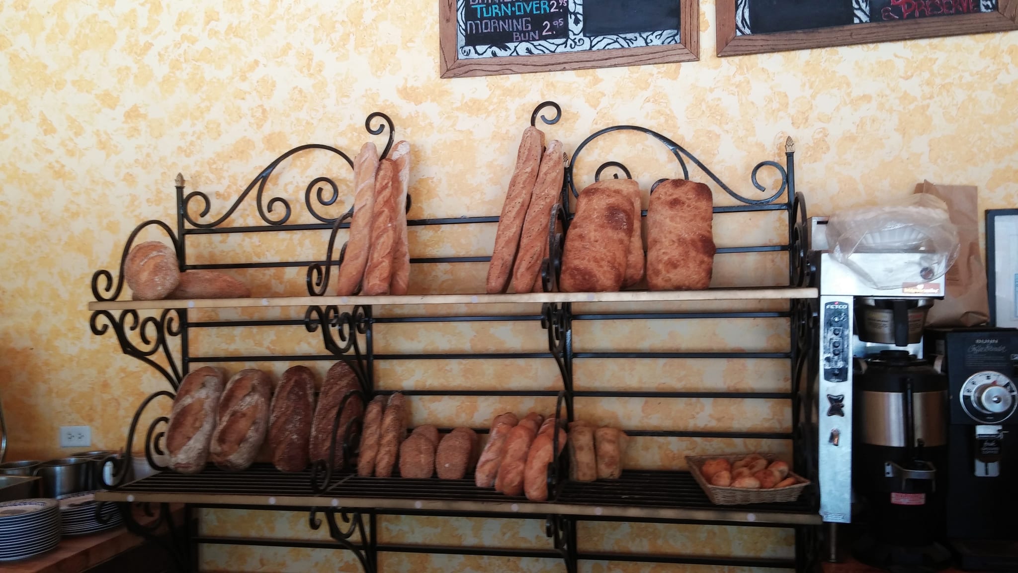 Wrought-iron bakery rack stacked with baguettes, ciabatta and rustic loaves