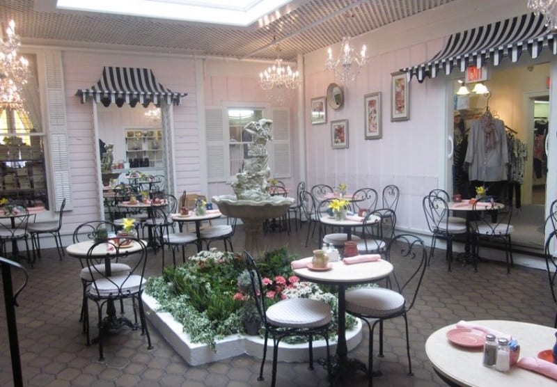 Pale pink tearoom with wrought iron chairs and striped awnings