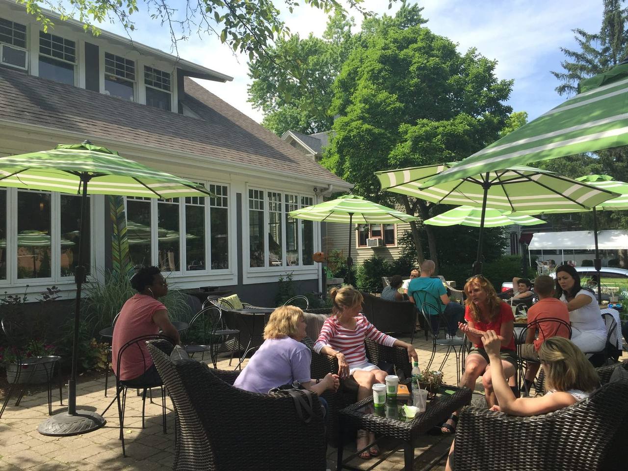 Brick patio of wicker chairs and green striped umbrellas full of customers