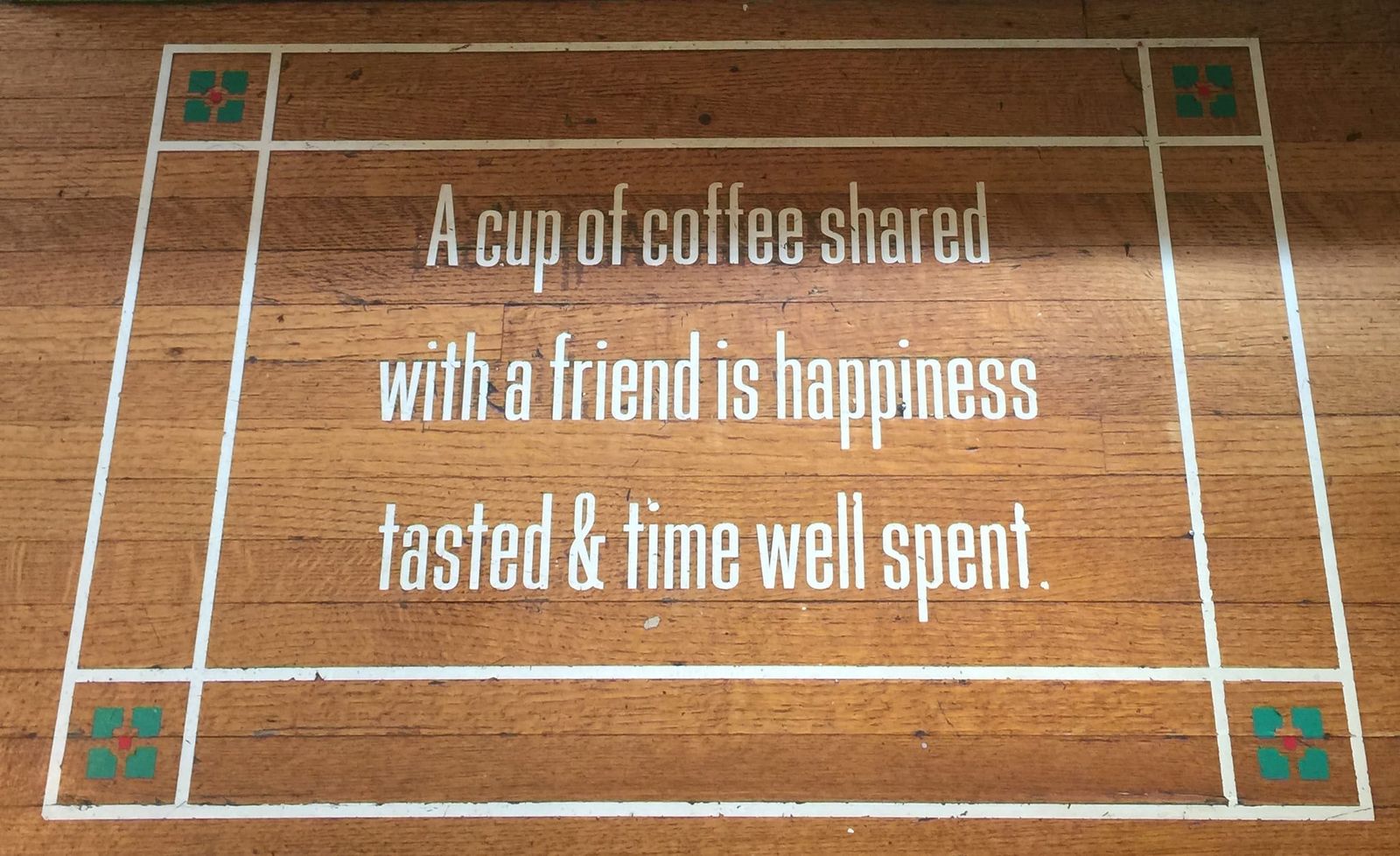Wood floor lettering: a cup of coffee shared with a friend is happiness
