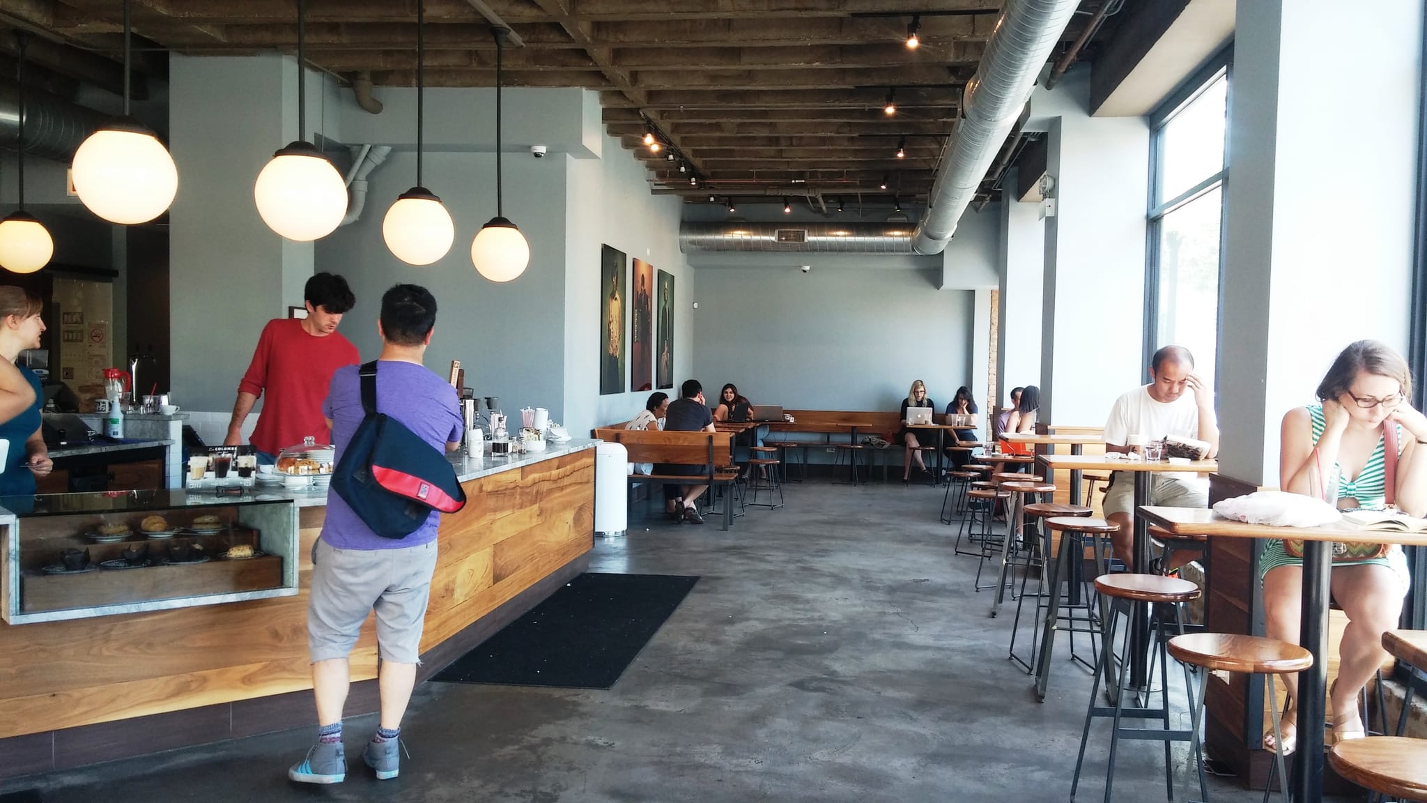 Long wood service counter, pendant globes and stool seating along windows