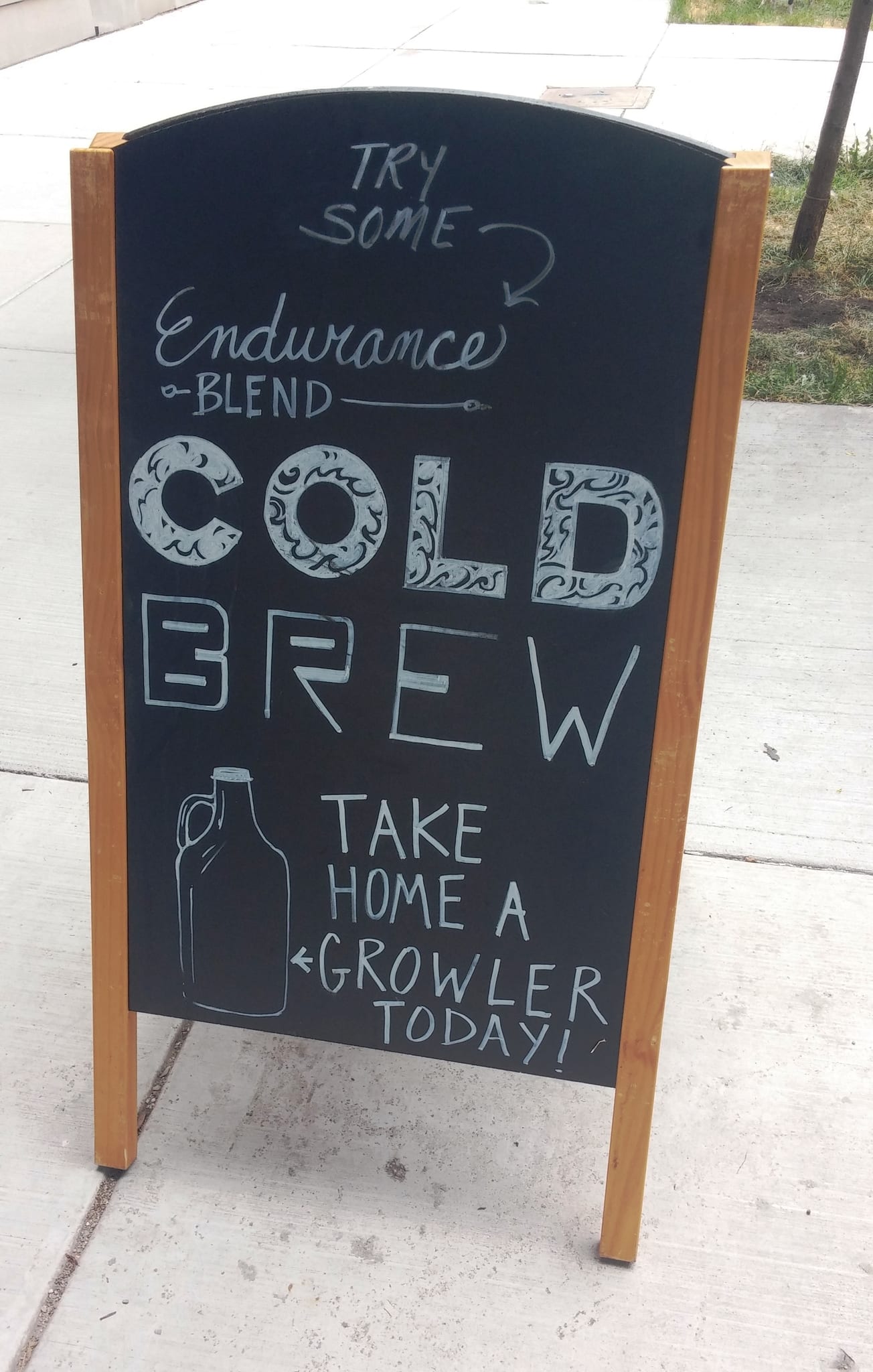 Sidewalk A-frame chalkboard advertising cold brew and take-home growlers