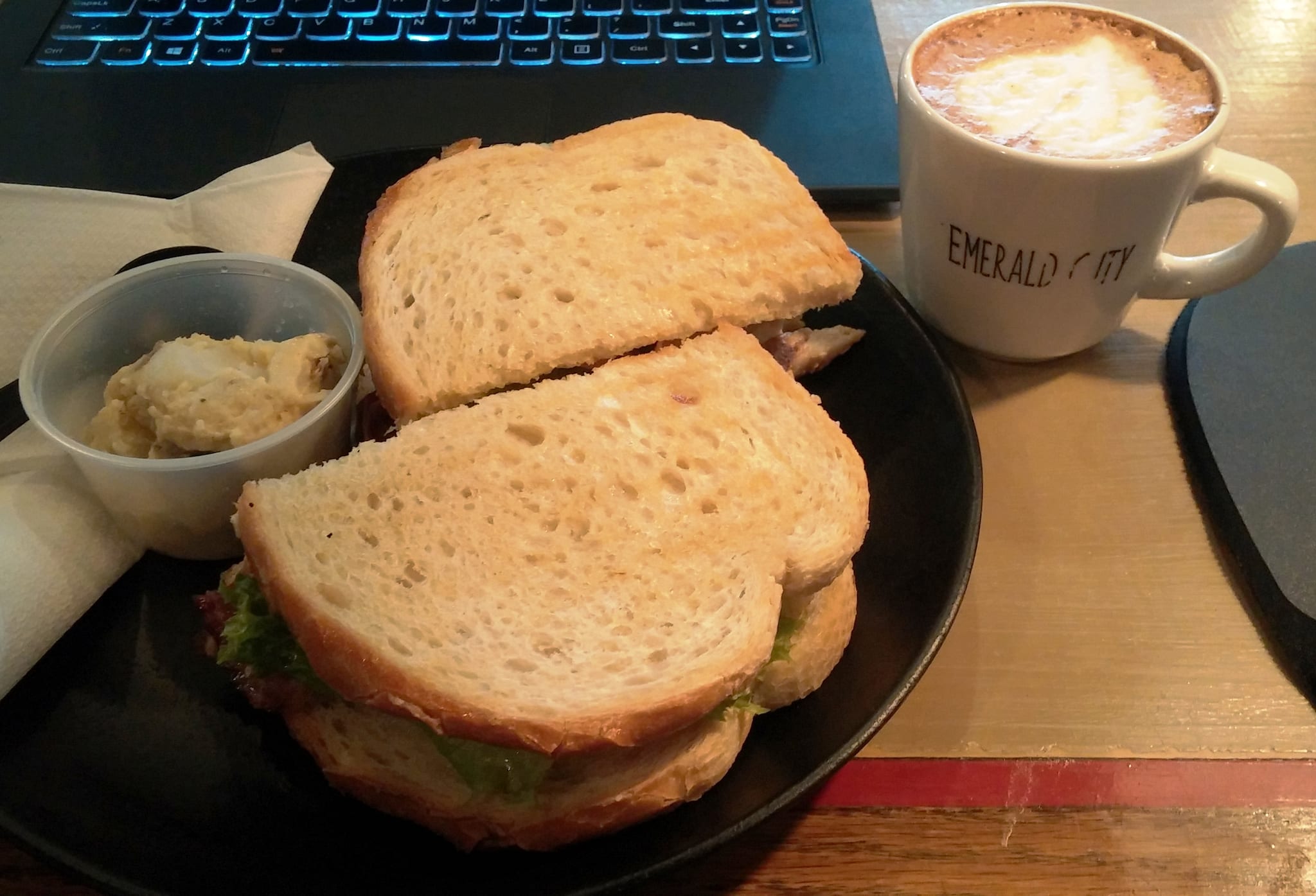 Sandwich on toasted bread with side salad and a frothy mocha