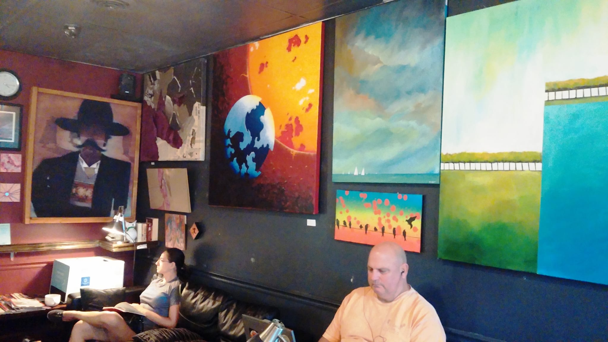 Lounge with leather couch and wall of colorful paintings for sale