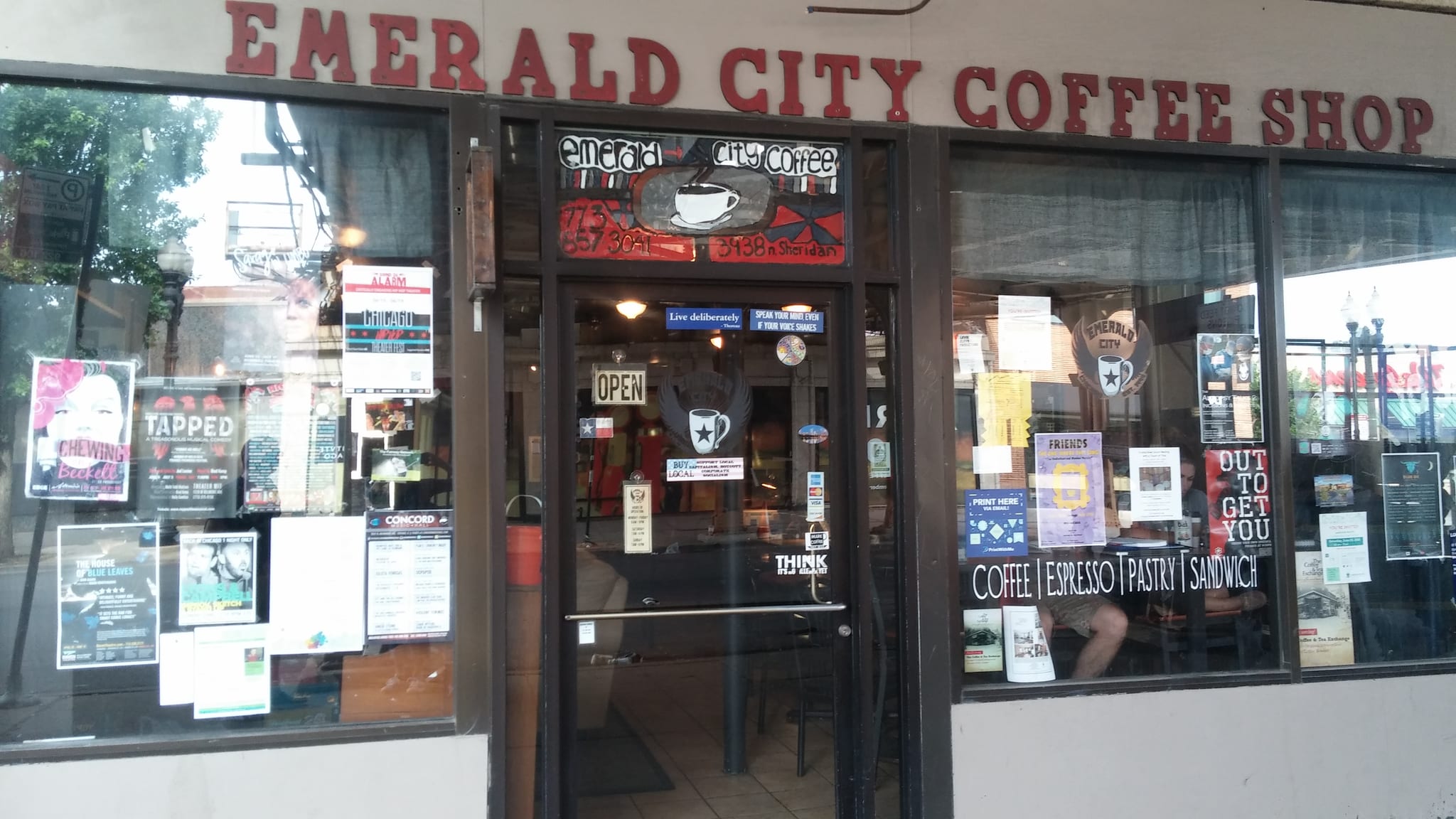 Storefront with red lettering and windows covered in theater posters and flyers