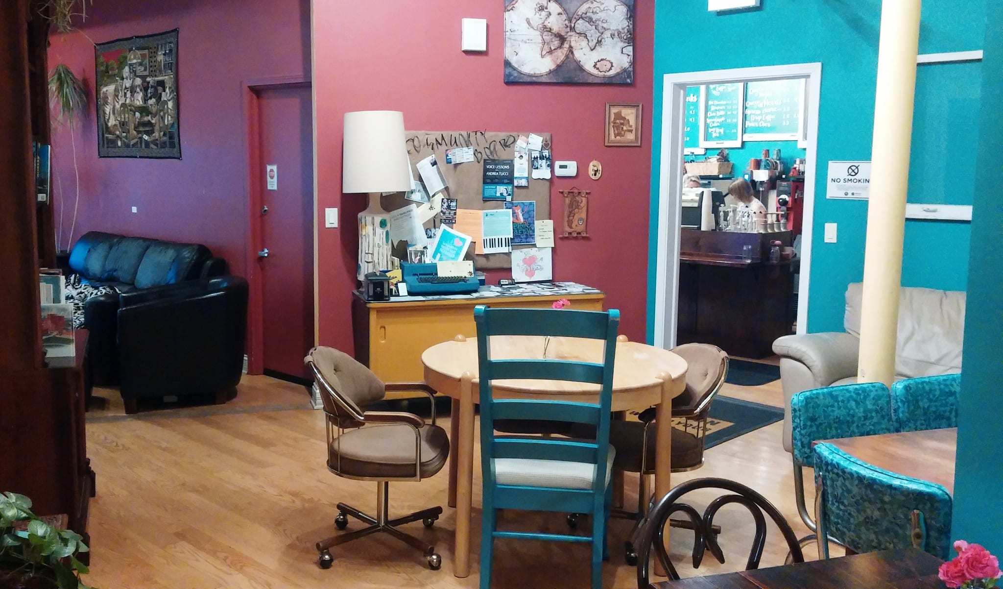 Front room with crimson and teal walls, community bulletin board and mixed chairs