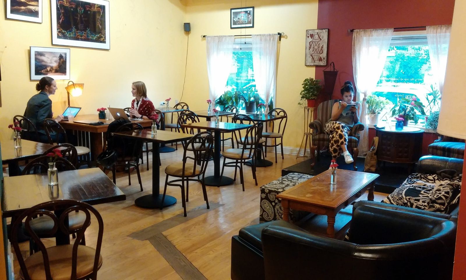 Sunlit dining room with bentwood chairs, framed art and customers on laptops