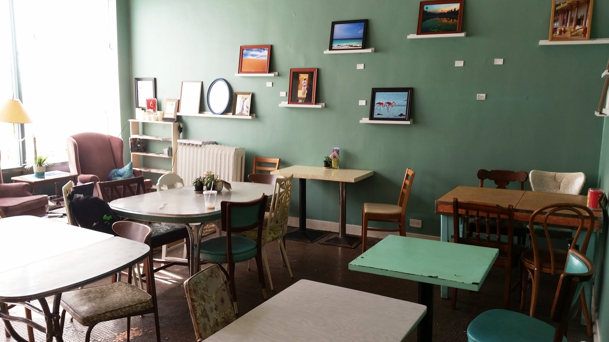 Mint green dining room with mismatched vintage tables and framed prints