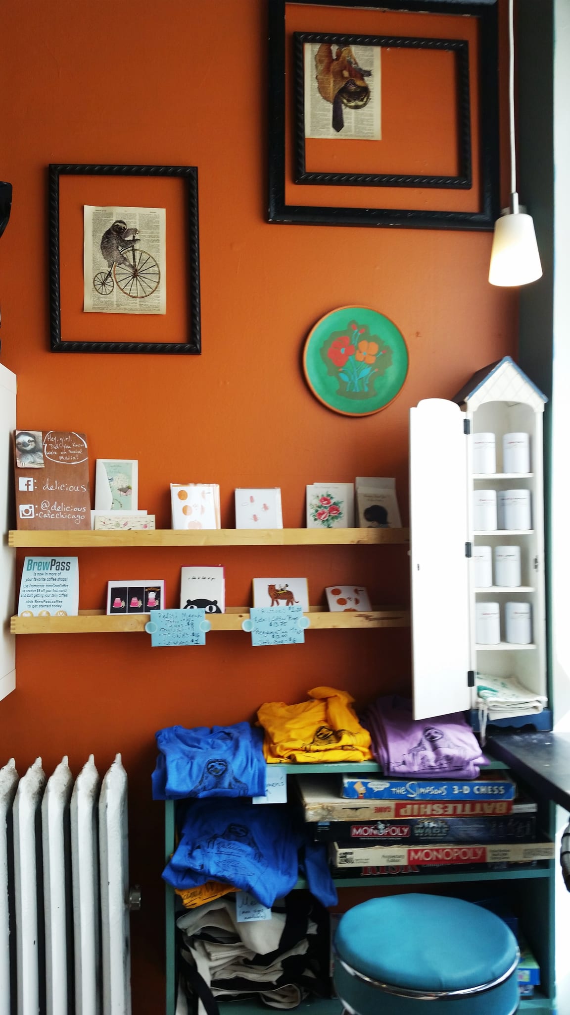 Orange wall with sloth prints, greeting cards and folded T-shirts