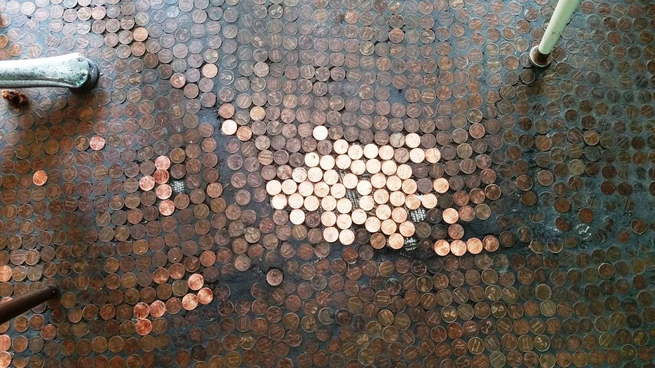 Floor tiled entirely with pennies under a chair leg