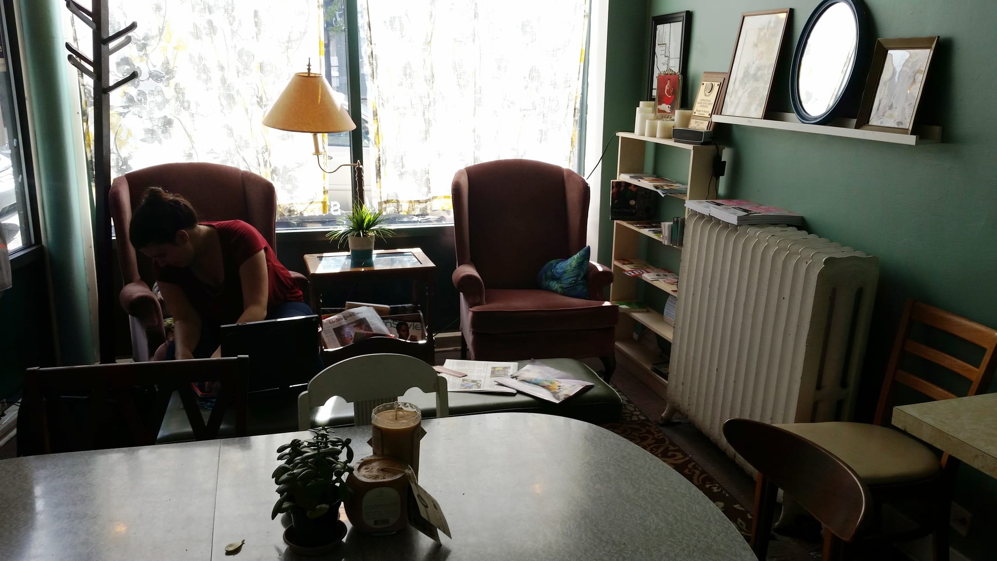Sunlit lounge corner with pink wingback armchairs and magazine rack
