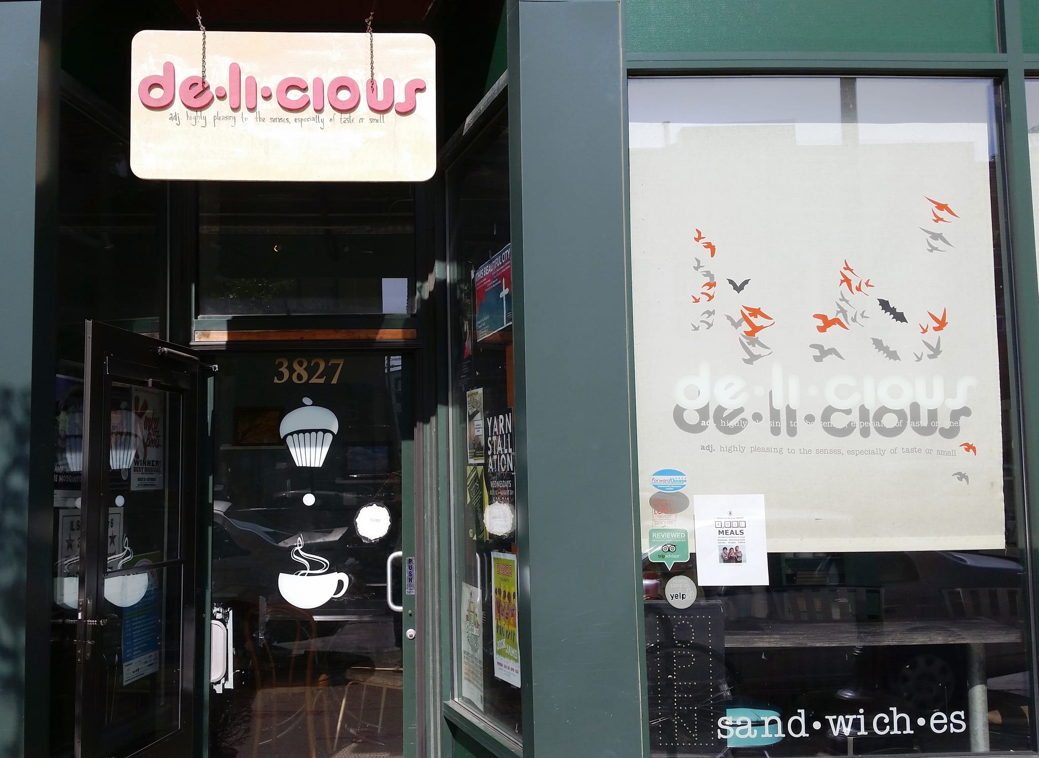 Green storefront with hanging de-li-cious sign and open door