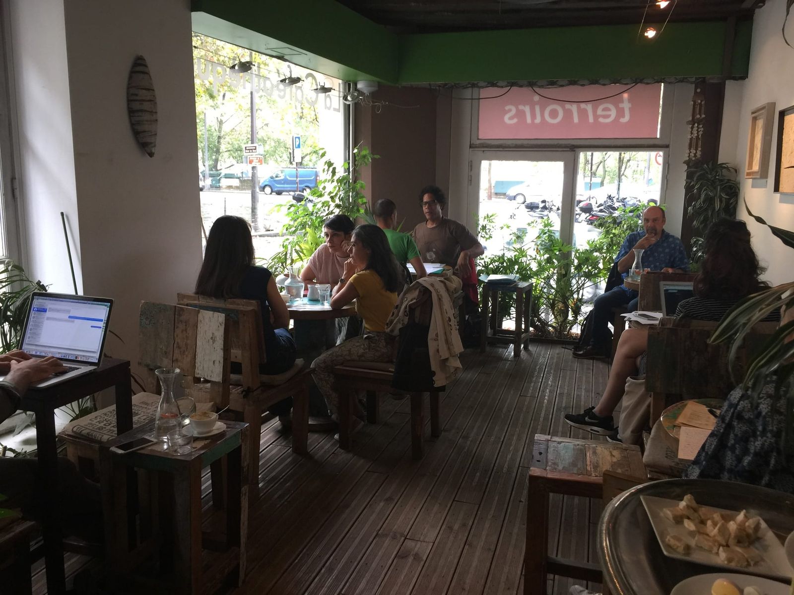 Reclaimed wood tables and leafy plants in daylit room with laptops