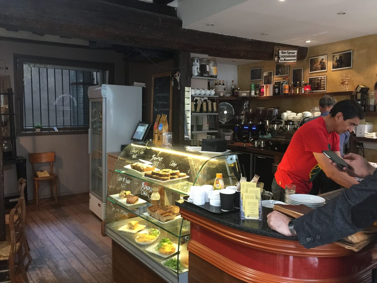 Curved wooden bar with lit pastry case and barista