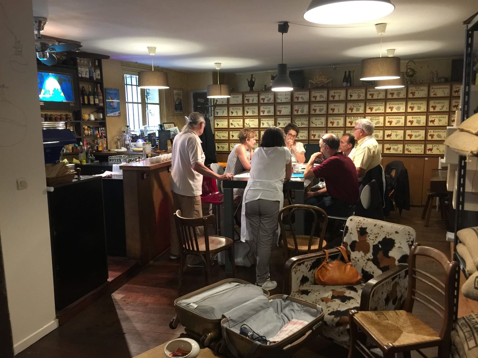 People seated at communal table below wall of country drawers