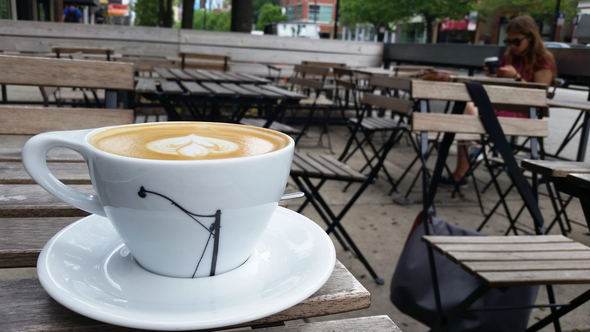 Cappuccino with rosetta latte art on a wooden patio table