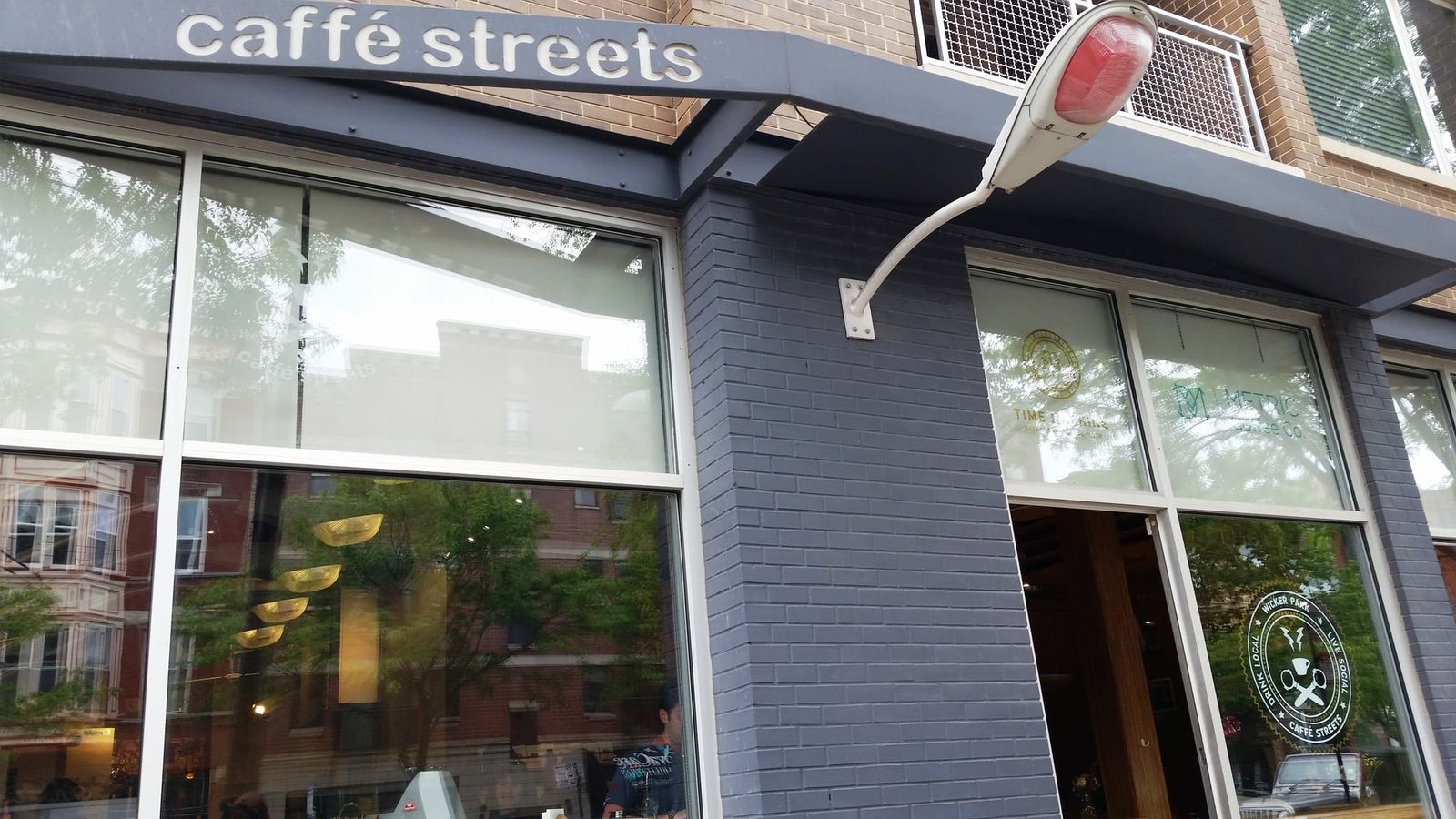 Grey brick corner storefront with caffe streets sign and streetlamp