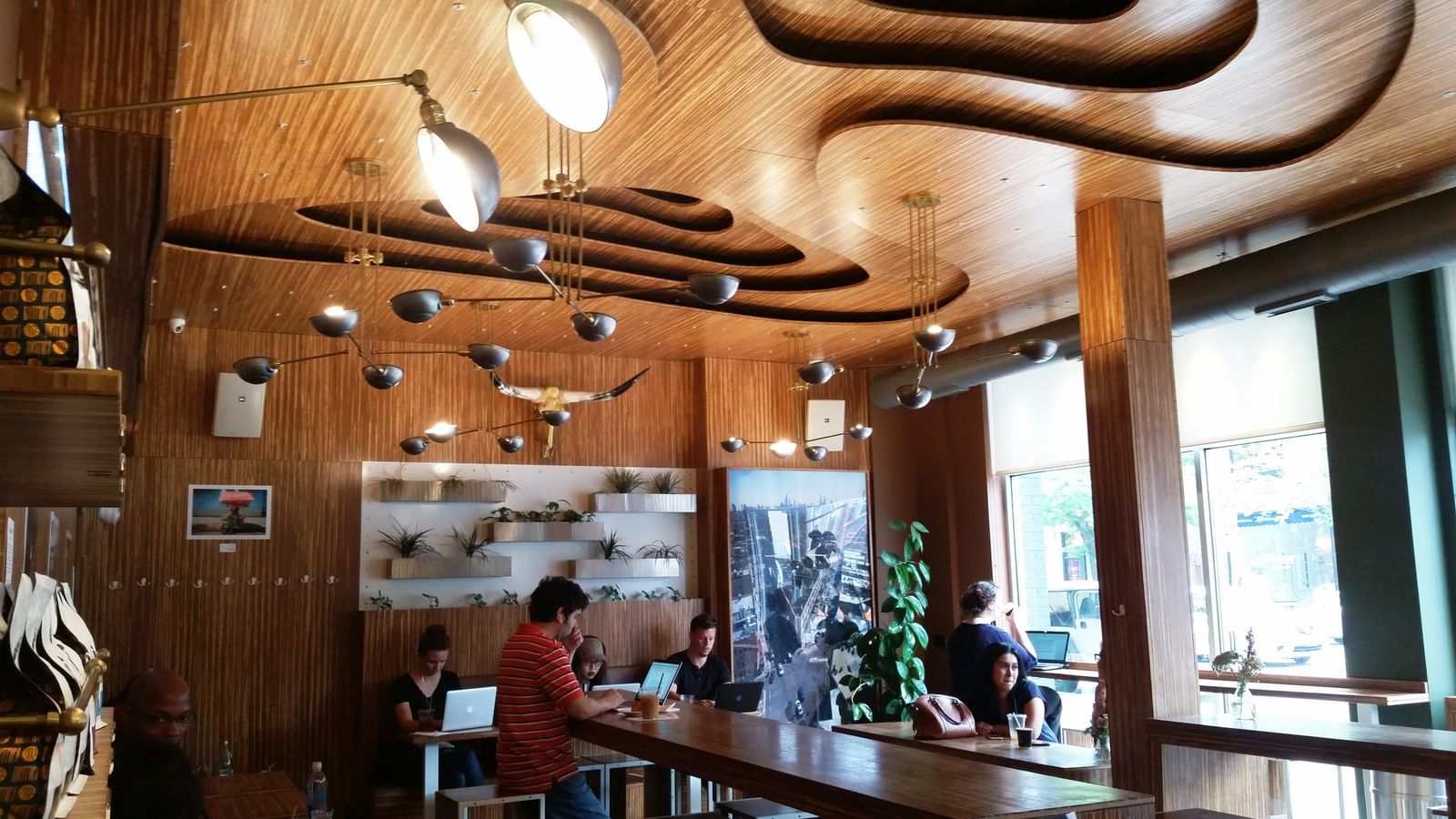 Sculpted wood ceiling over long communal table with laptop users