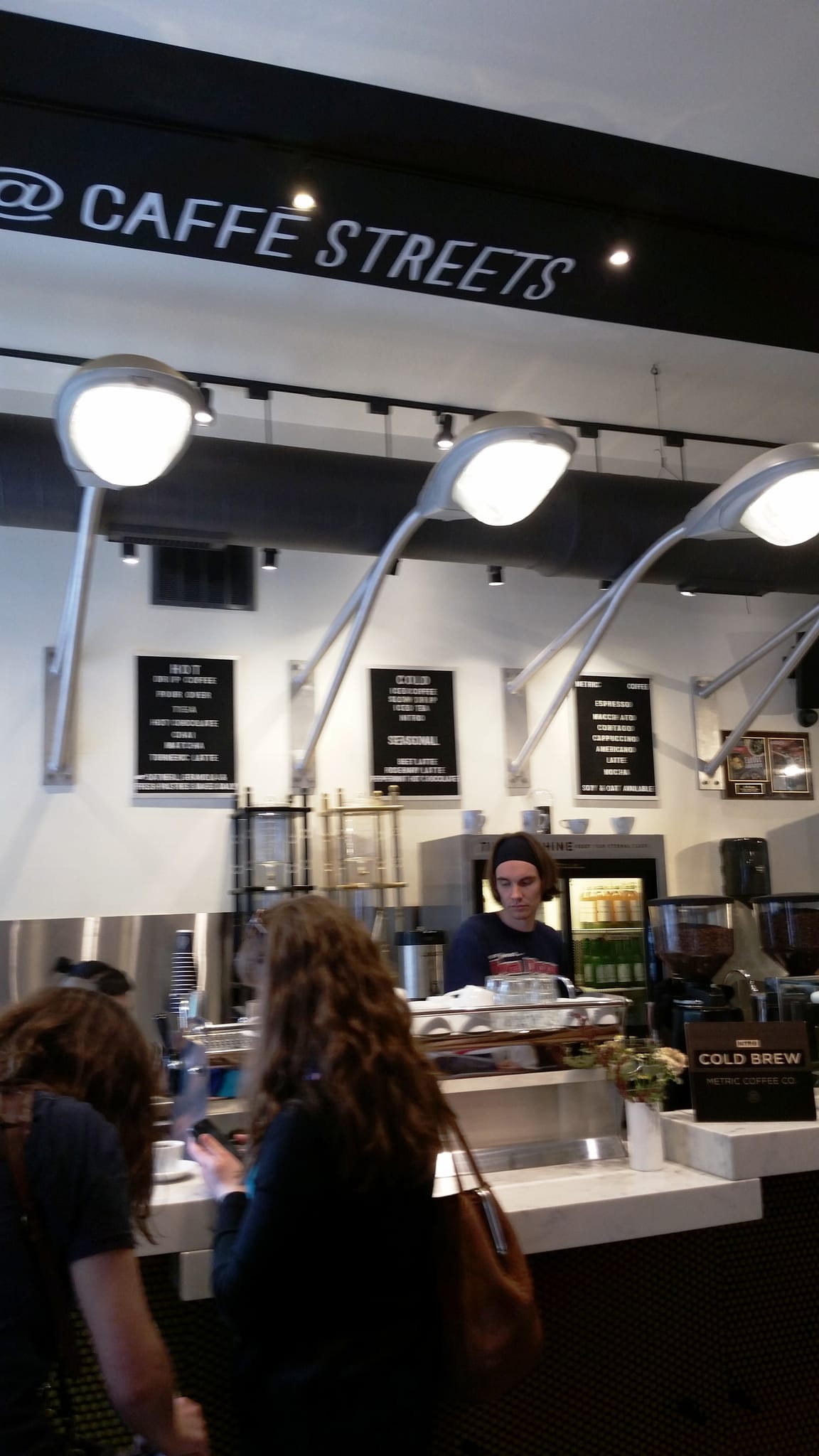 Counter under curved lamps with letterboard menus and cold brew sign