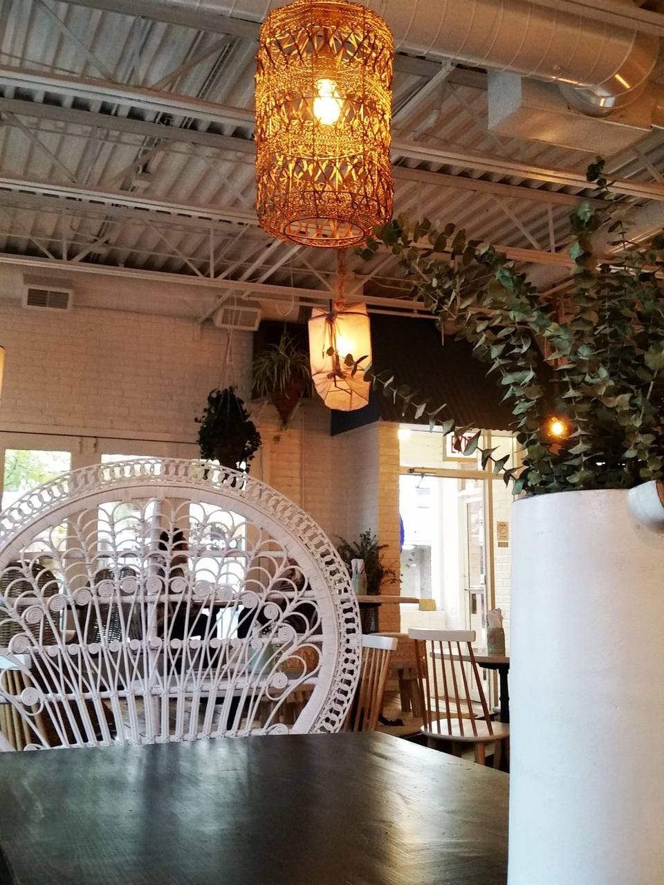 Woven pendant lamps and a white peacock chair beside a dark cafe table