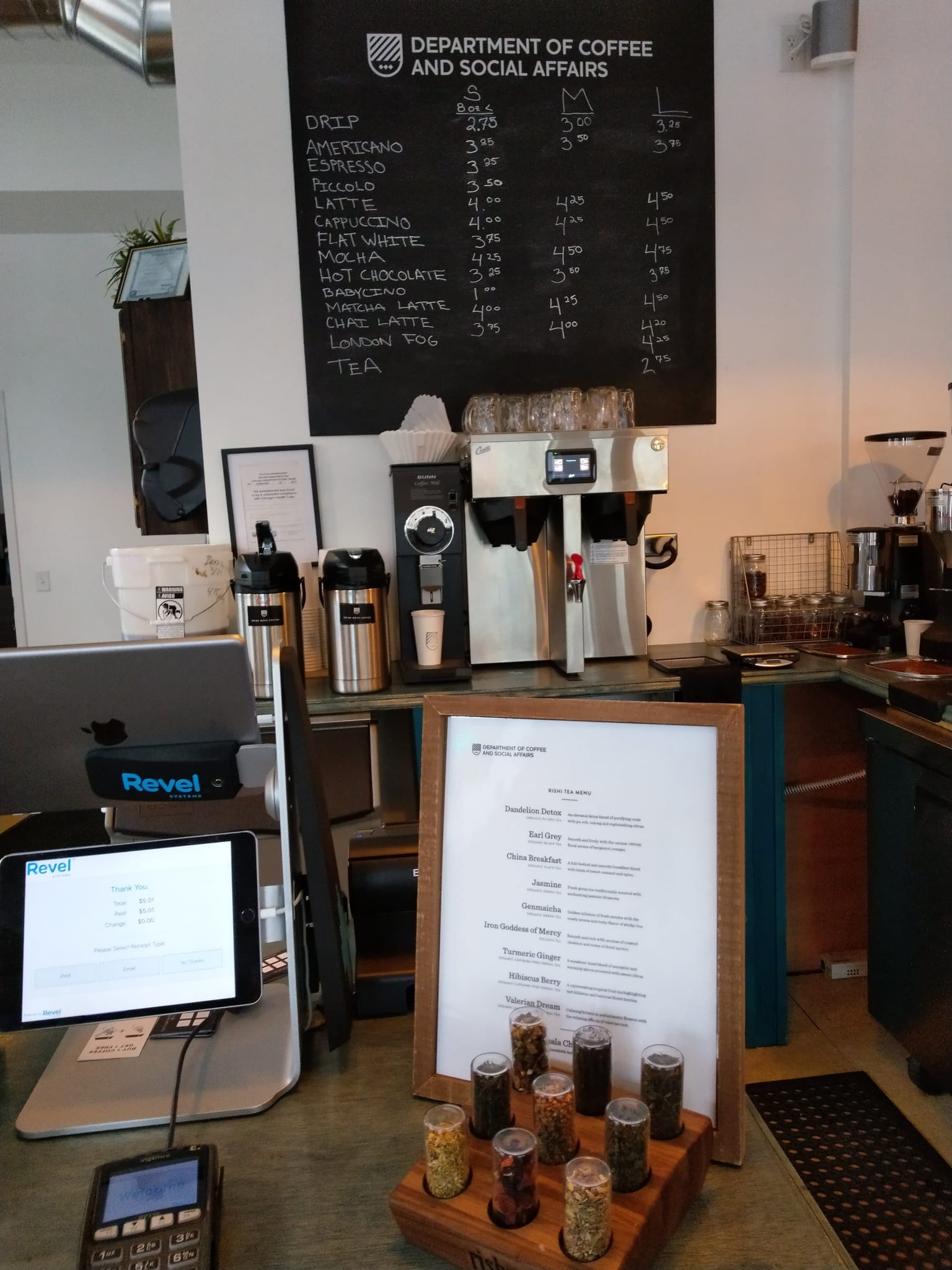 Register with tablet, brewers and a chalkboard price list above the bar