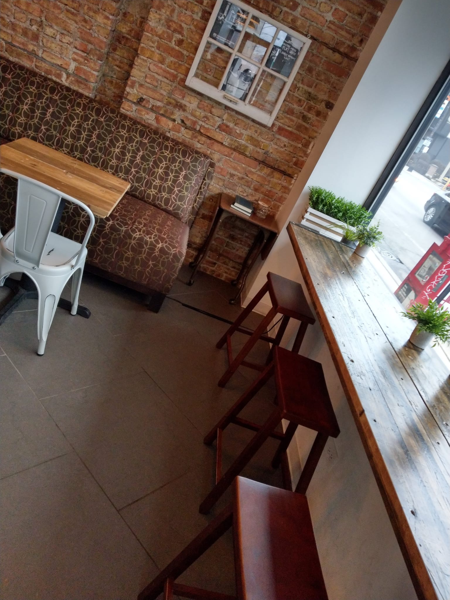 Patterned banquette against brick and wooden stools at a reclaimed-wood window bar