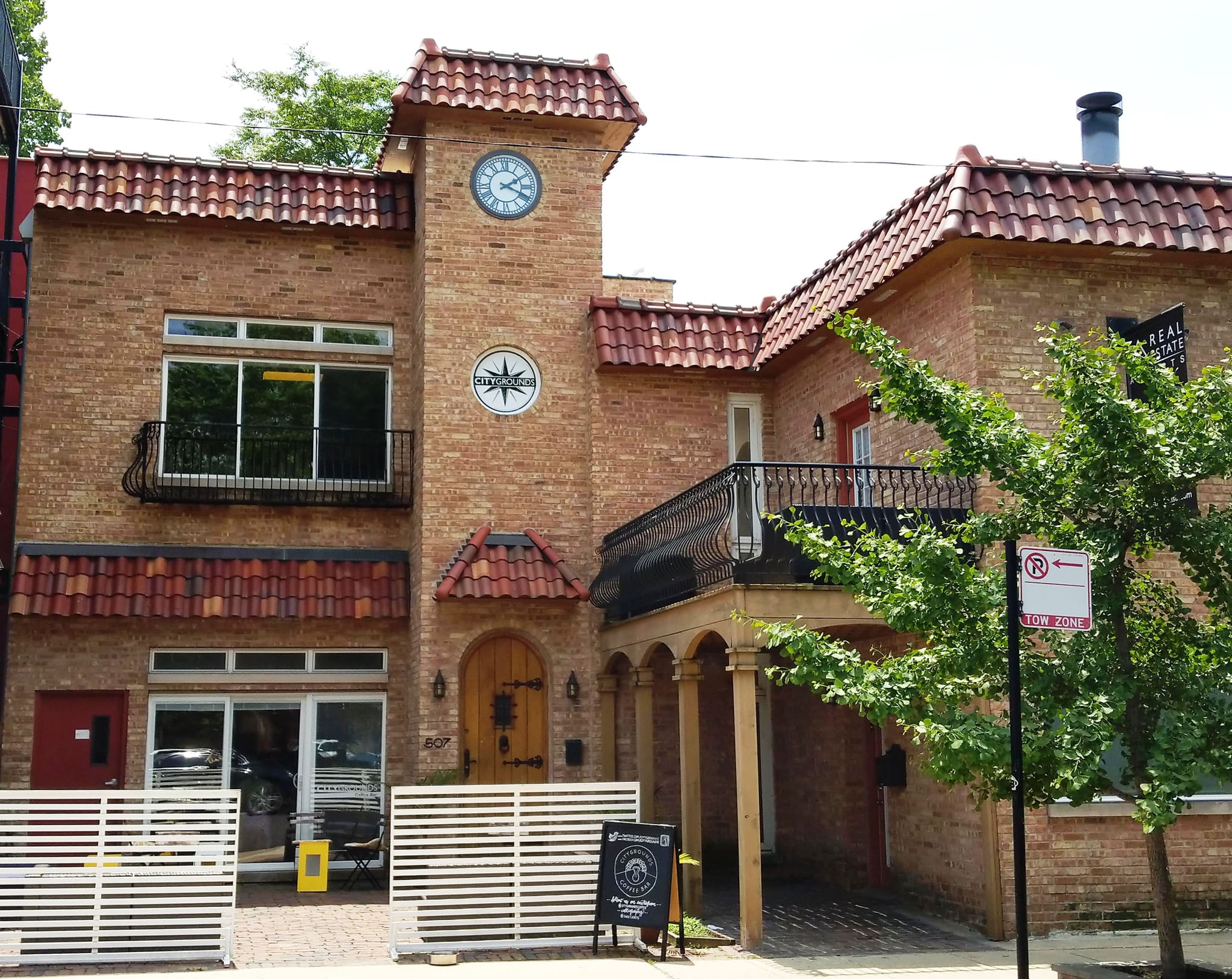Brick building with tiled roof, clock tower and a round coffee bar sign