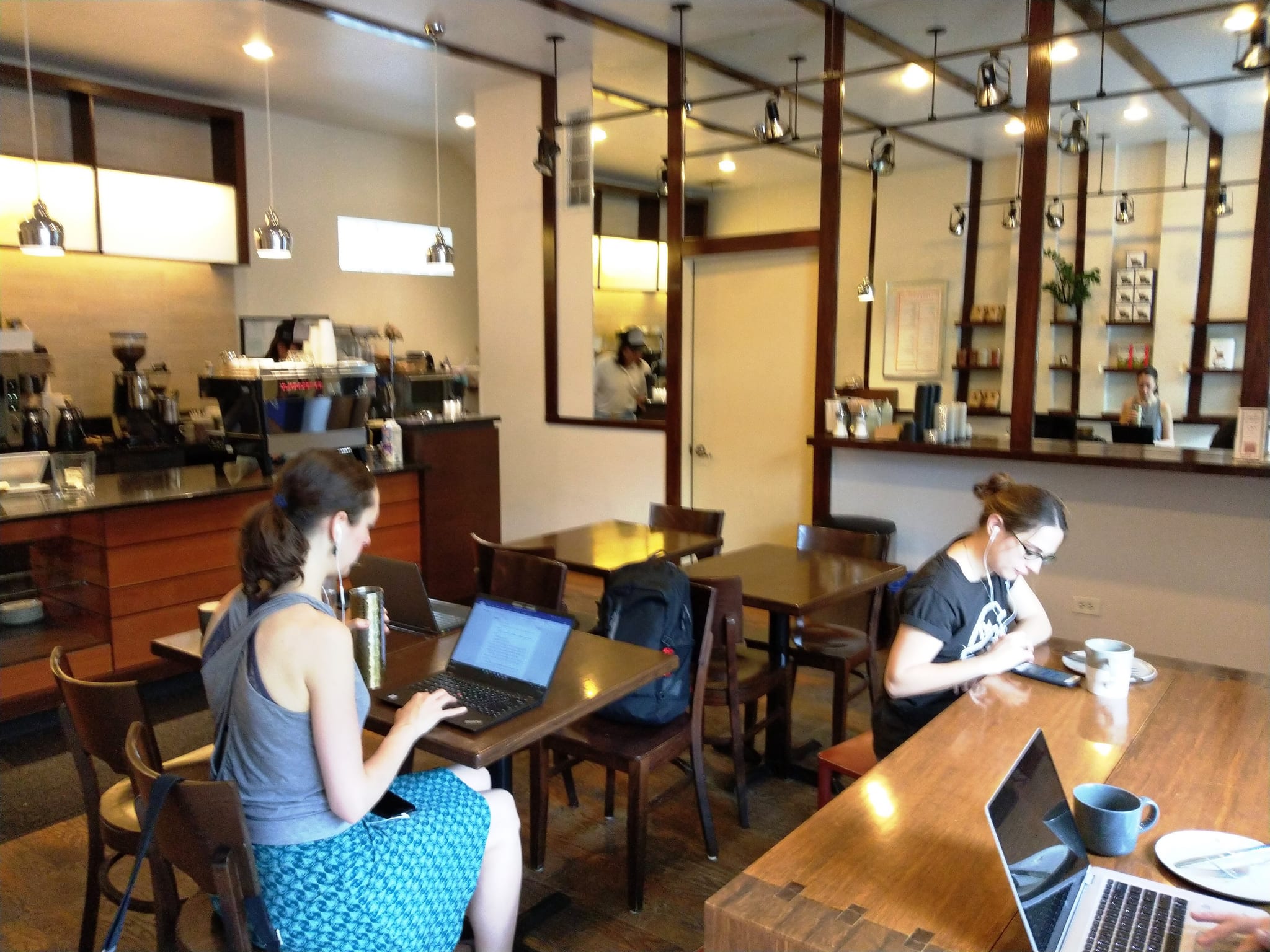 Cafe seating area with espresso counter, pendant lights and people working on laptops