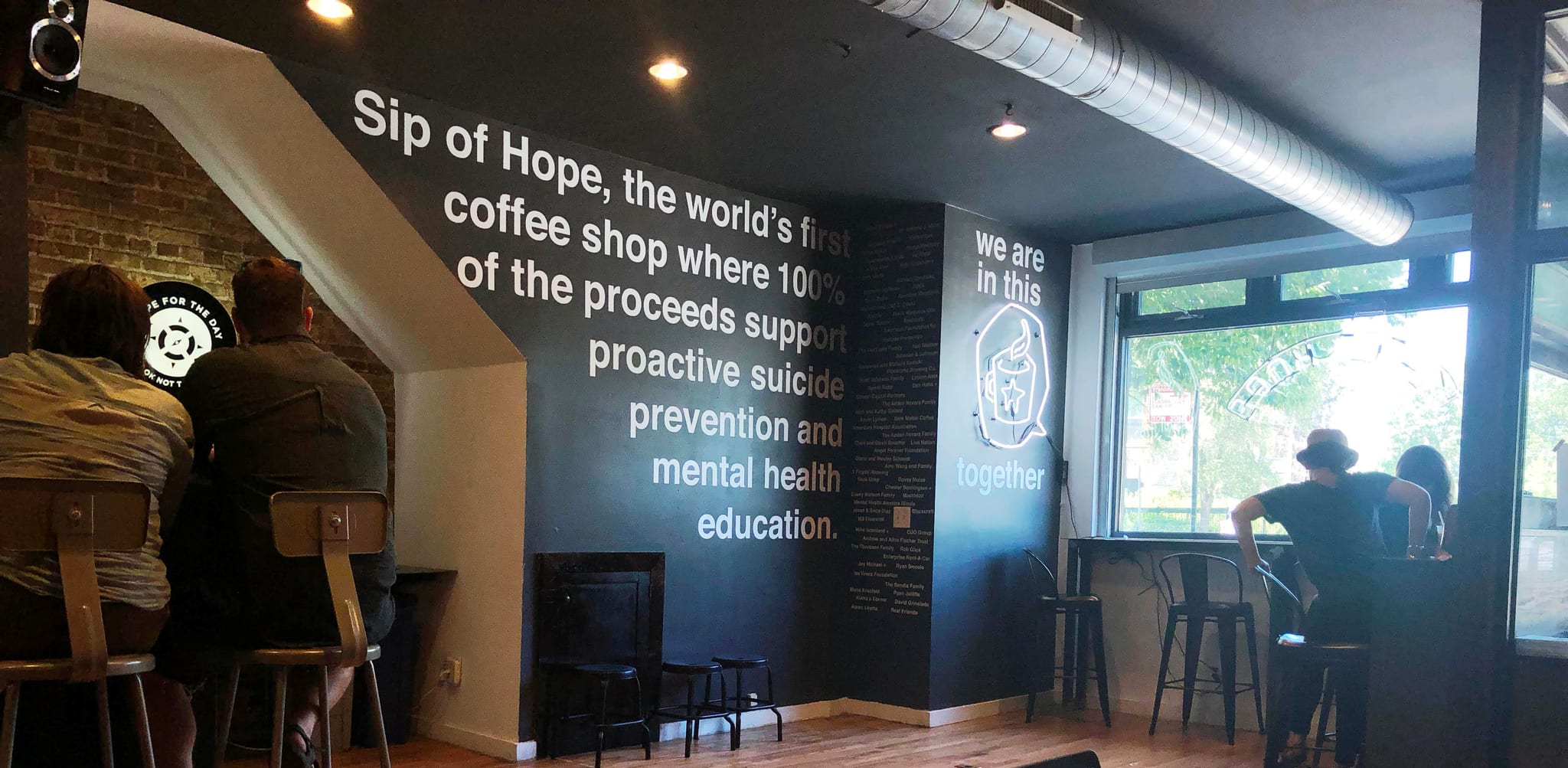 Dark wall painted with the shop mission statement and a neon sign