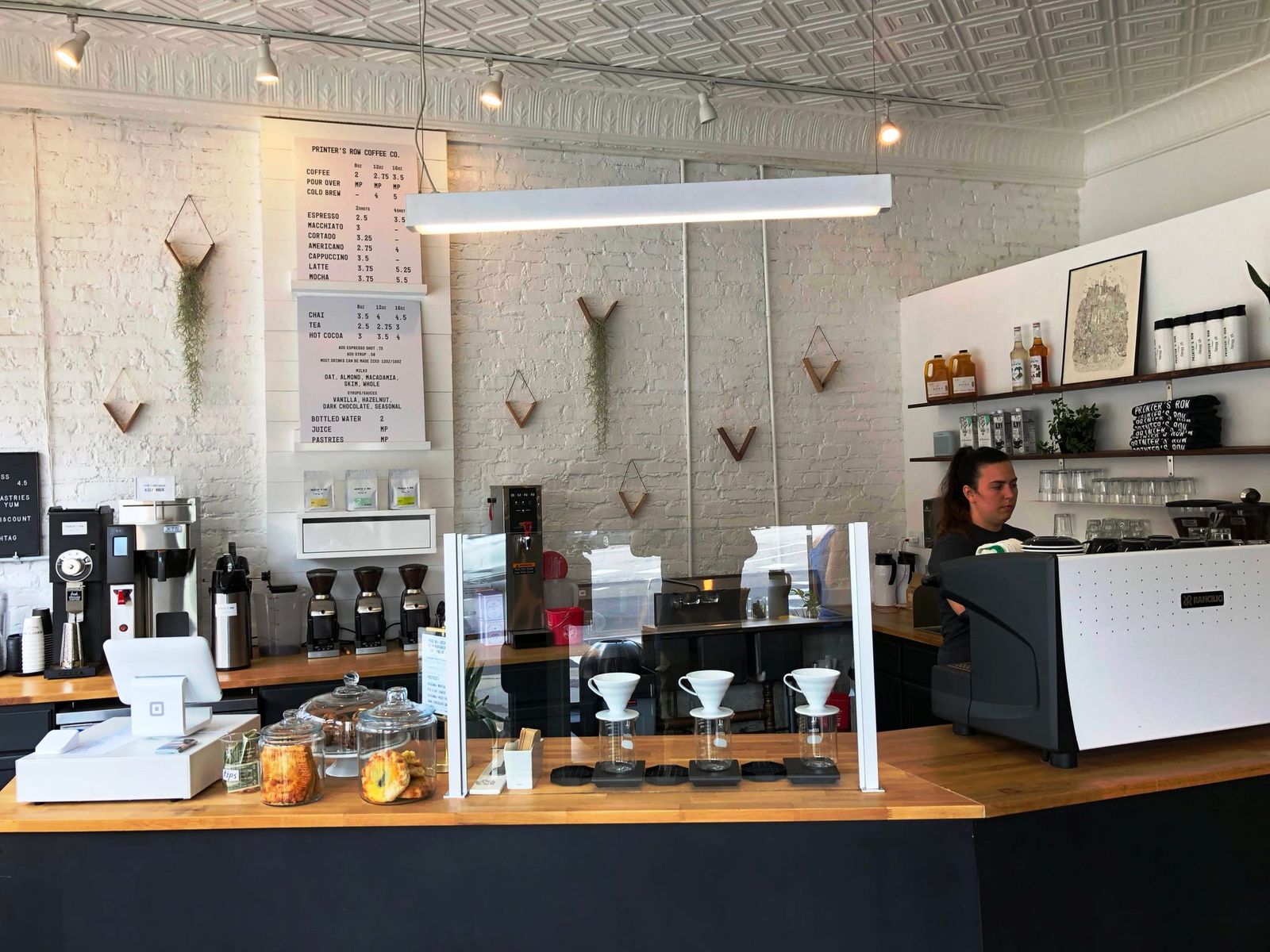 Wood counter with pour-over drippers, espresso machine and hanging price menus